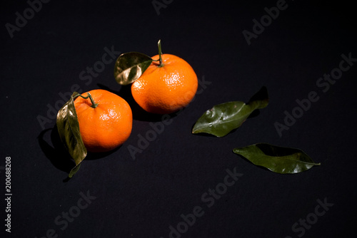 Photos Two citrus mandarin with leafes on black background isolated