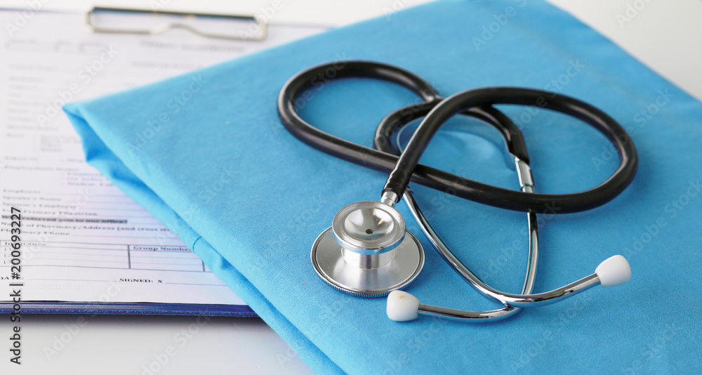 Stethoscope on a table with medical uniform Stethoscope on a table with medical uniform