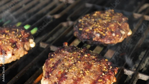 close up panning up shot of hamburgers cooking on a grill