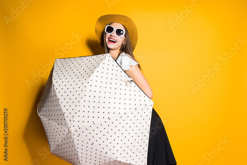 laughing fashionable model girl in sunglasses and hat posing with big umbrella
