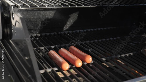 Close up of a chef placing hot dogs on a grill 