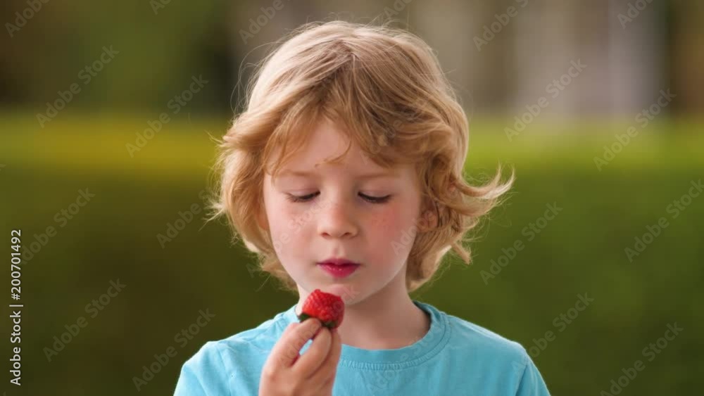 Blond boy eats delicious fresh strawberry Blond boy eats delicious fresh strawberry