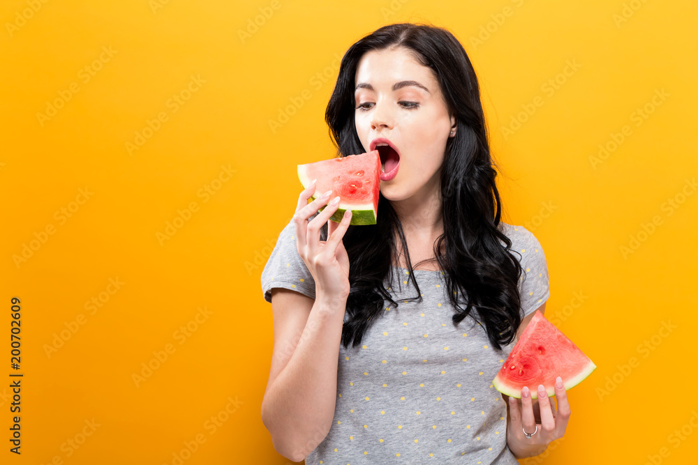 Happy young woman holding watermelon on a yellow background Happy young woman holding watermelon on a yellow background