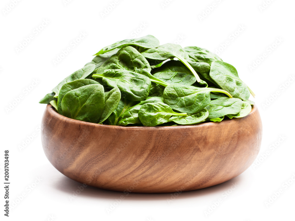Spinach leafs in wooden bowl isolated on white background Spinach leafs in wooden bowl isolated on white background