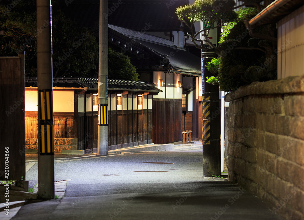 Quiet street runs by an old wooden house in Osaka, Japan