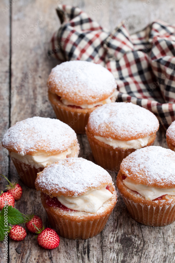 Cupcakes stuffed with white cream and wild strawberry on wooden table Cupcakes stuffed with white cream and wild strawberry on wooden table