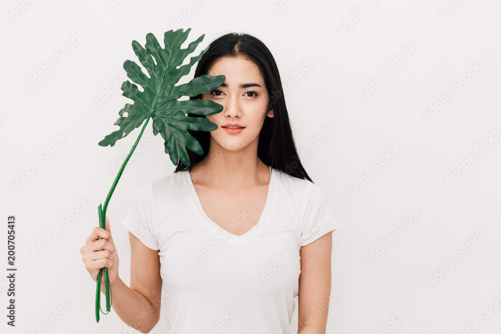 Portrait of beautiful woman behind green leaf.skin care and organic cosmetics concept Portrait of beautiful woman behind green leaf.skin care and organic cosmetics concept
