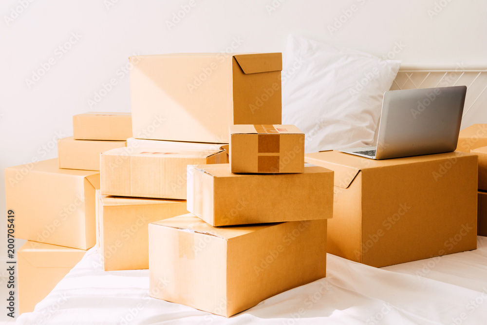 Pile of cardboard box and laptop computer on bed.Business online and delivery concept
