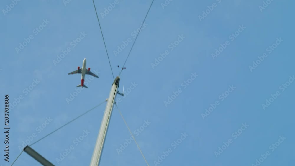 Airplane flies above yacht in blue cloudless sky Airplane flies above yacht in blue cloudless sky