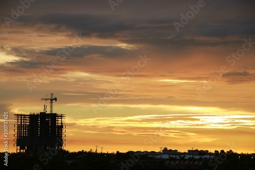 Skeleton of Building with Crane Scaffolding Under Construction against a Cloudy Sunset