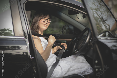 asian woman sitting in driver seat of sedan car fasten safety seat belt © stockphoto mania