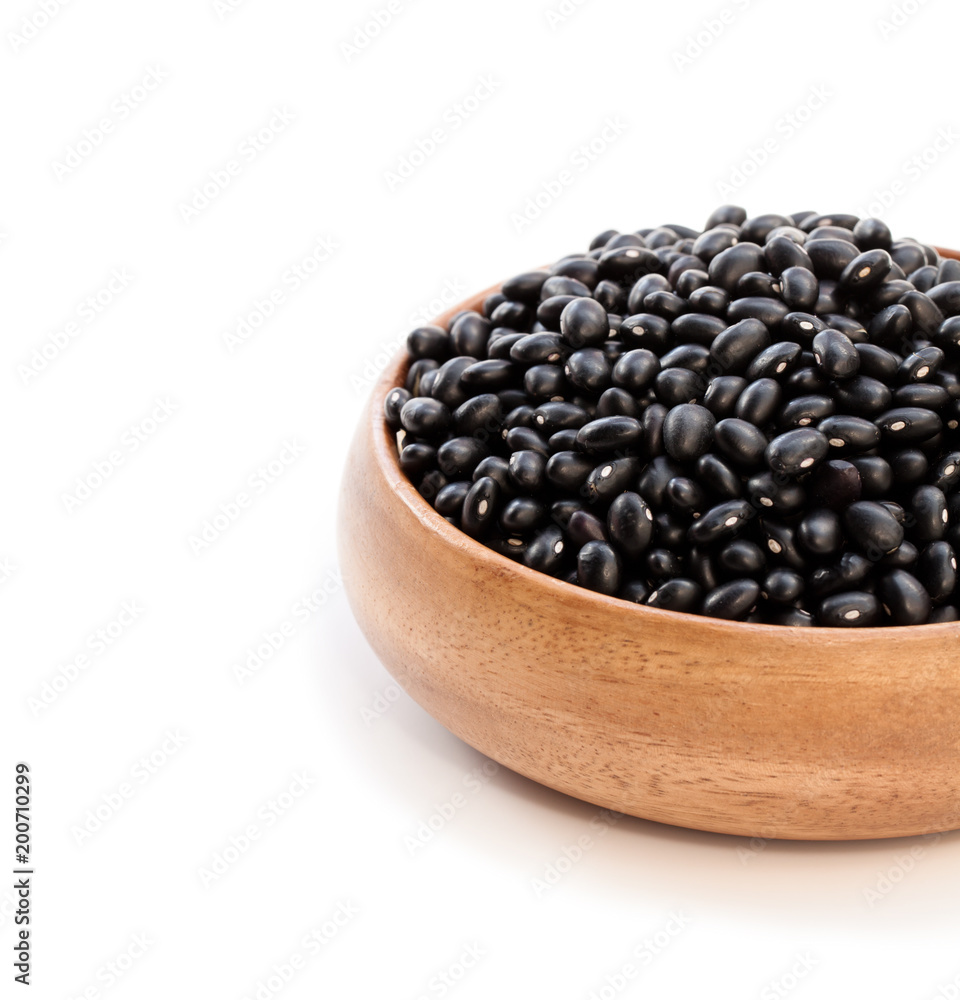 Raw black beans in wooden bowl isolated on white Raw black beans in wooden bowl isolated on white
