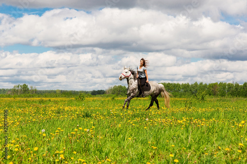 Woman riding on grey horse in the field