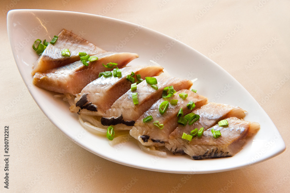 Sliced ??herring with green onion on a platter on the table Sliced ??herring with green onion on a platter on the table