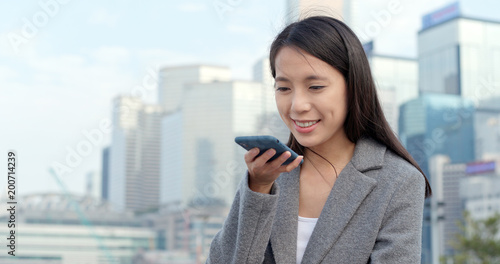 Canvas Print Businesswoman sending audio message on cellphone in city