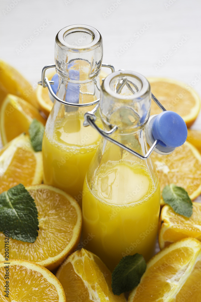 glass bottles with orange and straw on an orange background close-up. glass bottles with orange and straw on an orange background close-up.