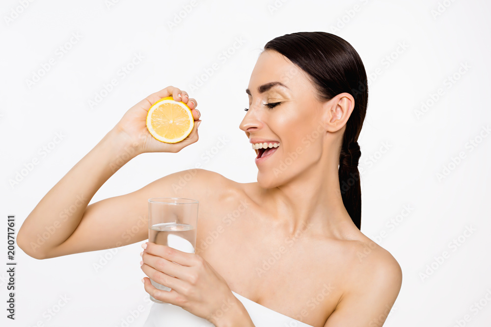 Young beautiful smiling woman with halfs of lemon in hands isolated on white Young beautiful smiling woman with halfs of lemon in hands isolated on white