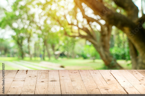 Empty wood table and defocused bokeh and blur background of garden trees in sunlight  display montage for product.