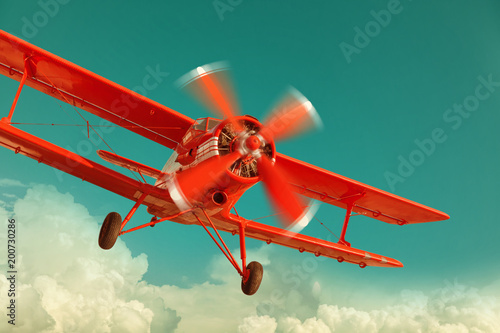 Red biplane flying in the cloudy sky. Retro style photo
