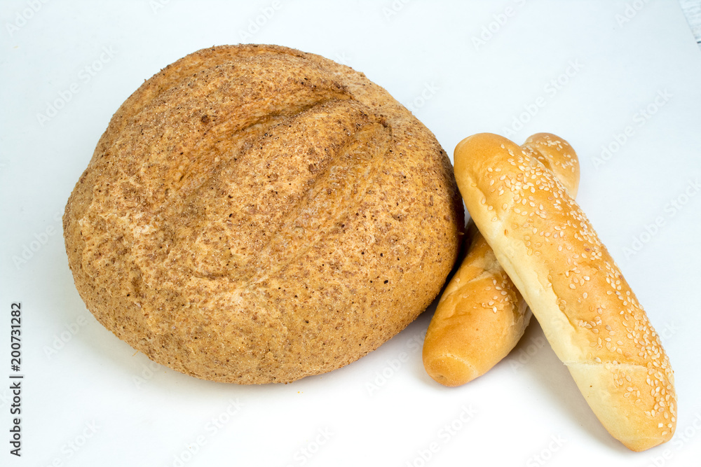 Many mixed breads and rolls of baked bread, on wooden table background.