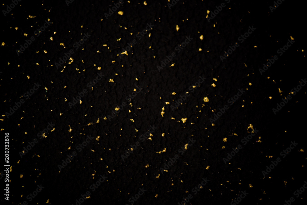 Gold glitter texture on a black background. Holiday background. Golden explosion of confetti. Golden grainy abstract texture on a black background. Design element.