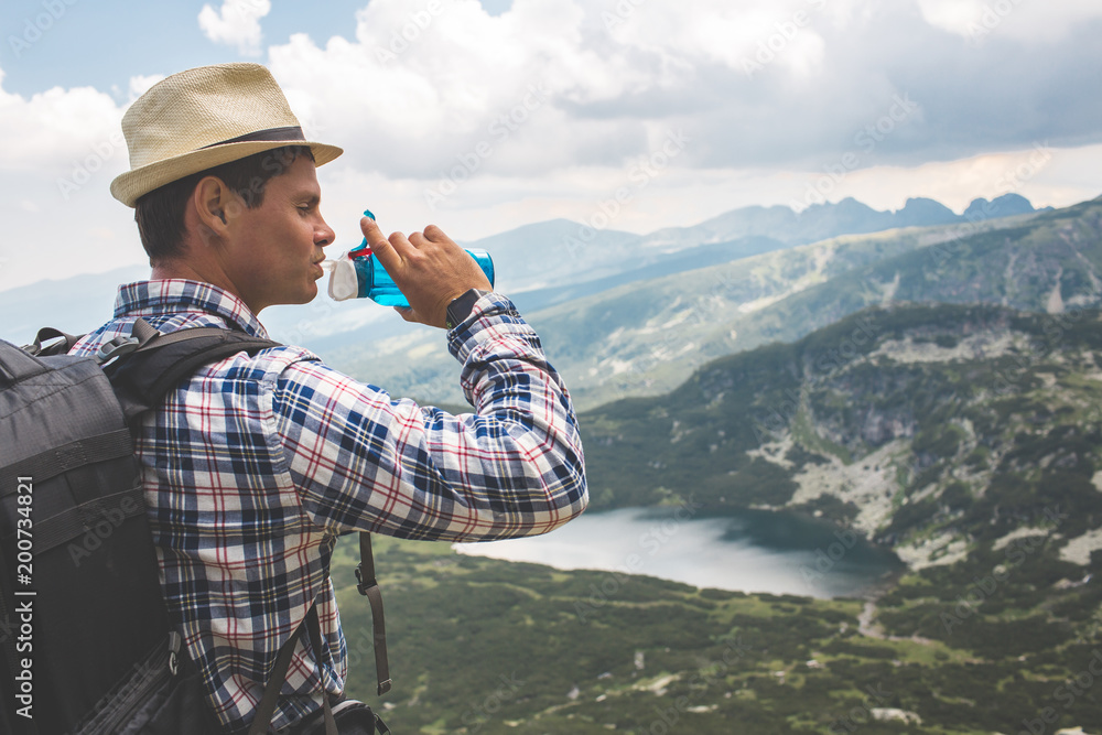 Obraz premium Traveler drinks water in the mountains