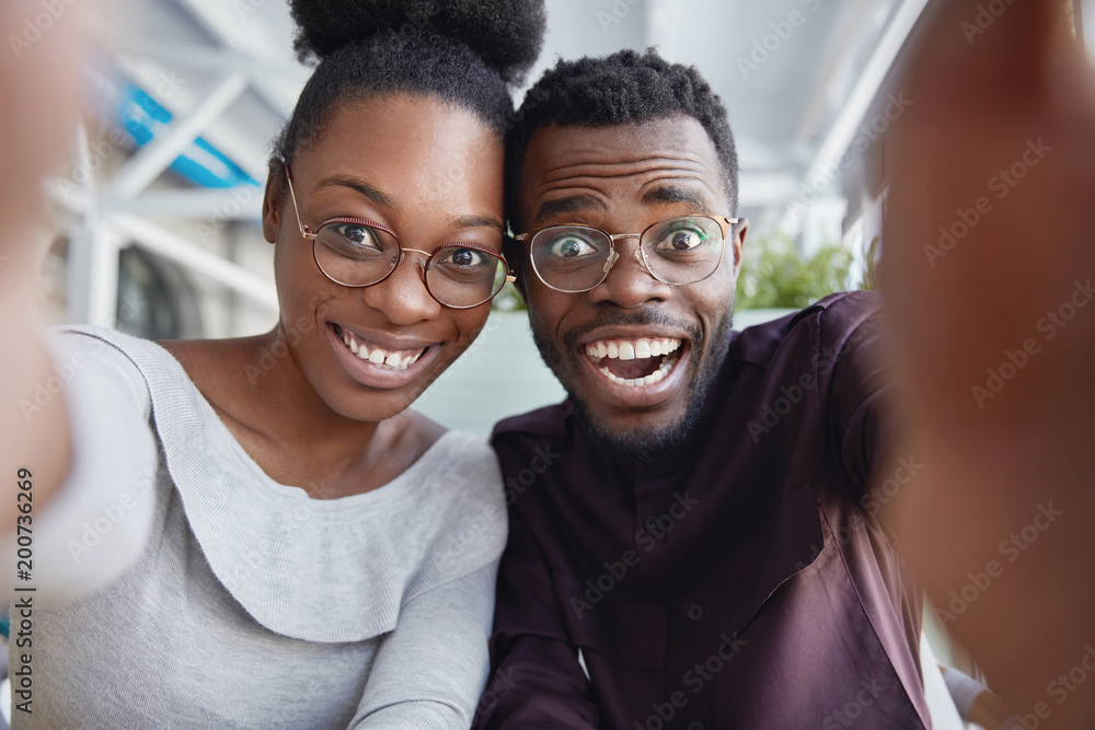 Joyful black male and female best friends have fun together, take picture of themselves or pose for making selfie, being in good mood after successful day. People, friedship, leisure, happiness Joyful black male and female best friends have fun together, take picture of themselves or pose for making selfie, being in good mood after successful day. People, friedship, leisure, happiness