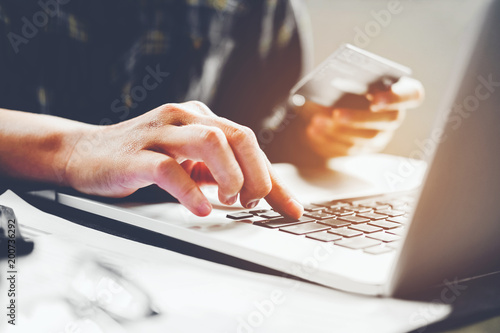 Man's hands typing laptop keyboard and holding credit card online shopping concept photo