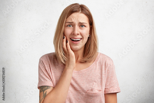 Desperate sorrorful female model has problem in life, frowns face in dissatisfaction, going to cry, needs support from close people, has attractive appearance, isolated over white background photo