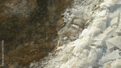 Small ice floes float near the shore and pram on the shore on a cold winter day. Warm undercurrents. Close-up photo