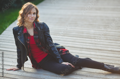 Beautiful young woman in black leather jacket. Outdoor portrait in city park