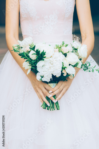 young bride holding a wedding bouquet in the shape of a heart in hands photo