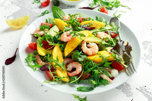 Fresh Avocado, Shrimps, Mango salad with lettuce green mix, cherry tomatoes, herbs and olive oil, lemon dressing. healthy food