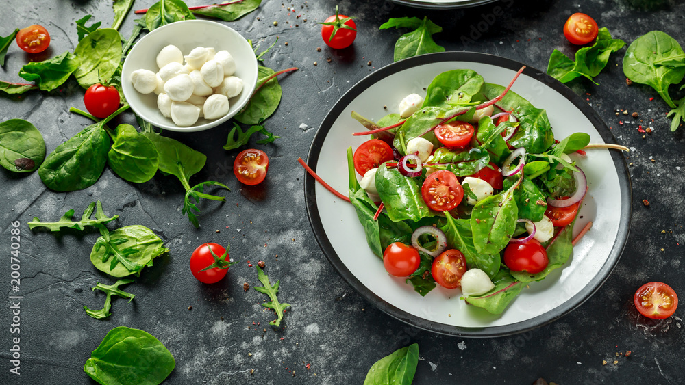 Fototapeta premium Fresh Cherry Tomato, Mozzarella salad with green lettuce mix and red onion. served on plate. healthy food.