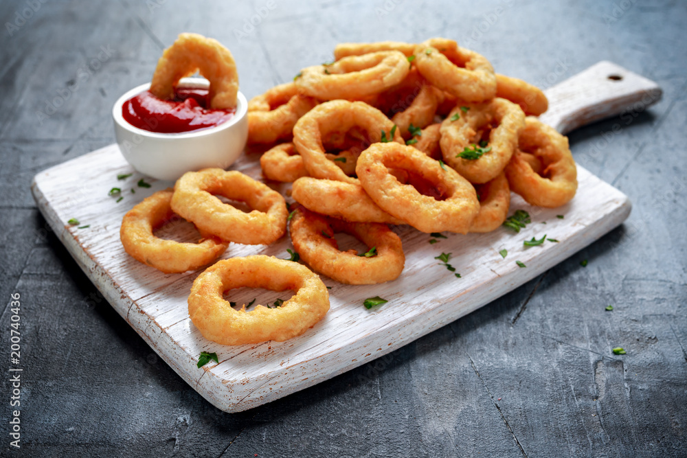 Fried Onion Rings with Ketchup on white cutting board. Fried Onion Rings with Ketchup on white cutting board.