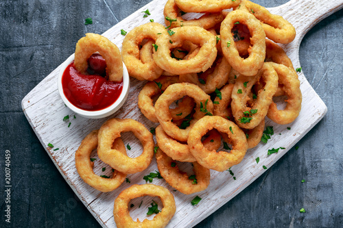 Fried Onion Rings with Ketchup on white cutting board. photo