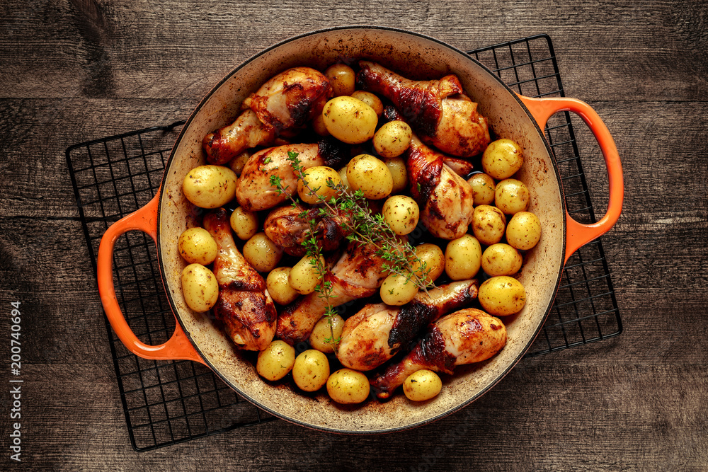 Oven baked Chicken drumsticks and new baby potatoes with thyme in pan, ready to serve Oven baked Chicken drumsticks and new baby potatoes with thyme in pan, ready to serve
