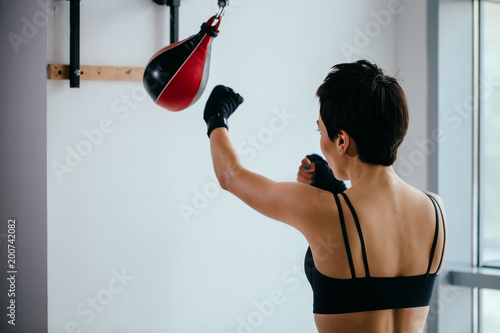 back view shot of slim woman with short hair training for boxing championat. concept of martial art photo