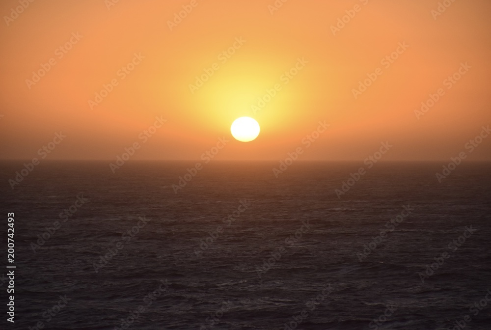 Bright orange sunset lowering peacefully over the ocean