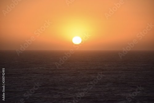 Bright orange sunset lowering peacefully over the ocean