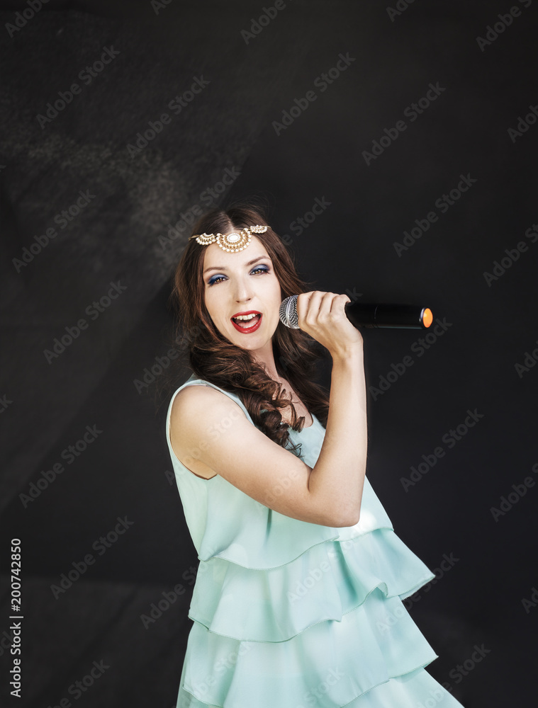 Portrait of beautiful singing woman in a light blue dress on black background. Portrait of beautiful singing woman in a light blue dress on black background.