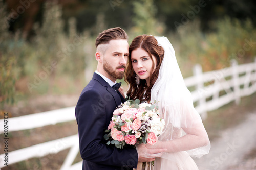 Married couple posing outdoors close up. Looking at camera. 20s.