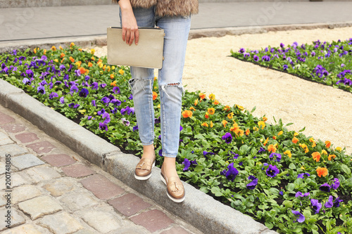 Woman in light blue jeans and golden leather shoes with handbag