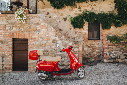 In the courtyard of an old house in Italy there is a red scooter