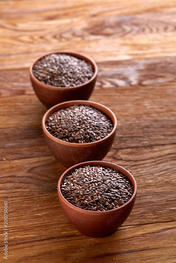 Flax seeds in wooden bowl on rustic wooden background, top view, selective focus Flax seeds in wooden bowl on rustic wooden background, top view, selective focus