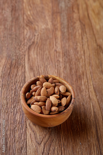 Tasty almond on a wooden plate over wooden background, top view, close-up, selective focus.