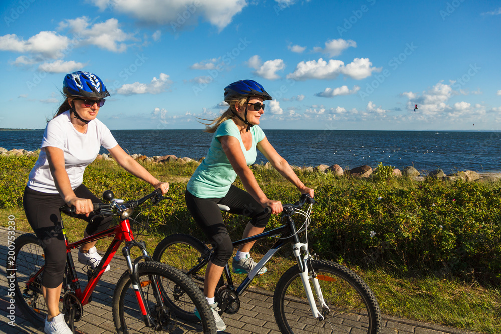Women riding bicycles at seaside