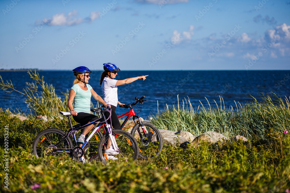 Obraz premium Women riding bicycles at seaside