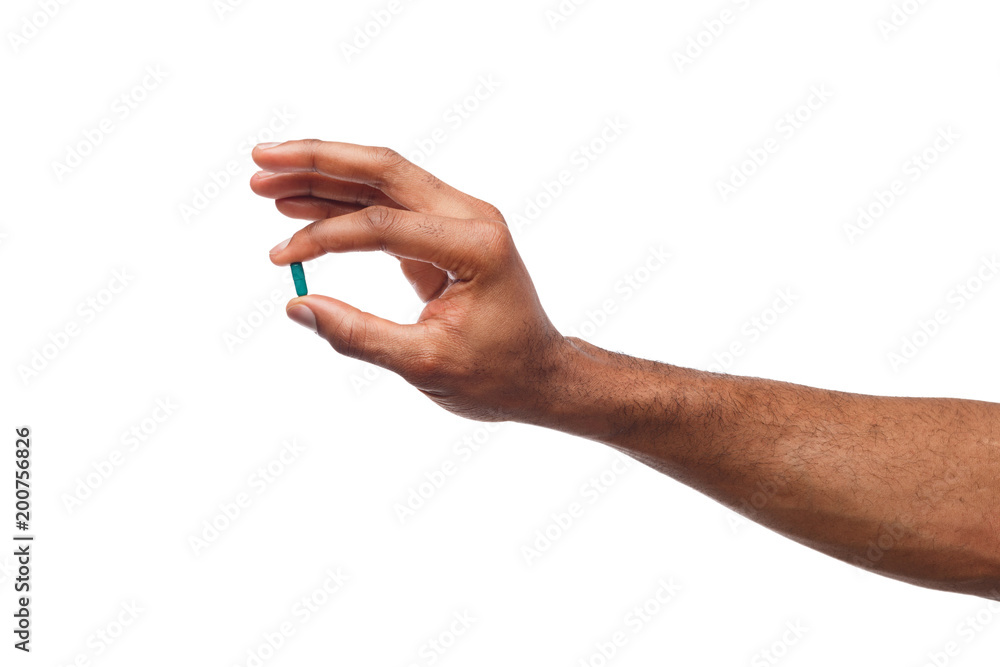 Black hand holding a pill isolated on white background Black hand holding a pill isolated on white background