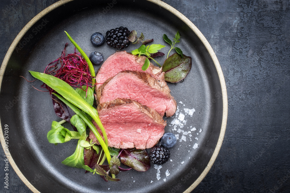 Traditional barbecue aged sliced fillet steak with wild garlic and fruits top view on a plate with copy space Traditional barbecue aged sliced fillet steak with wild garlic and fruits top view on a plate with copy space